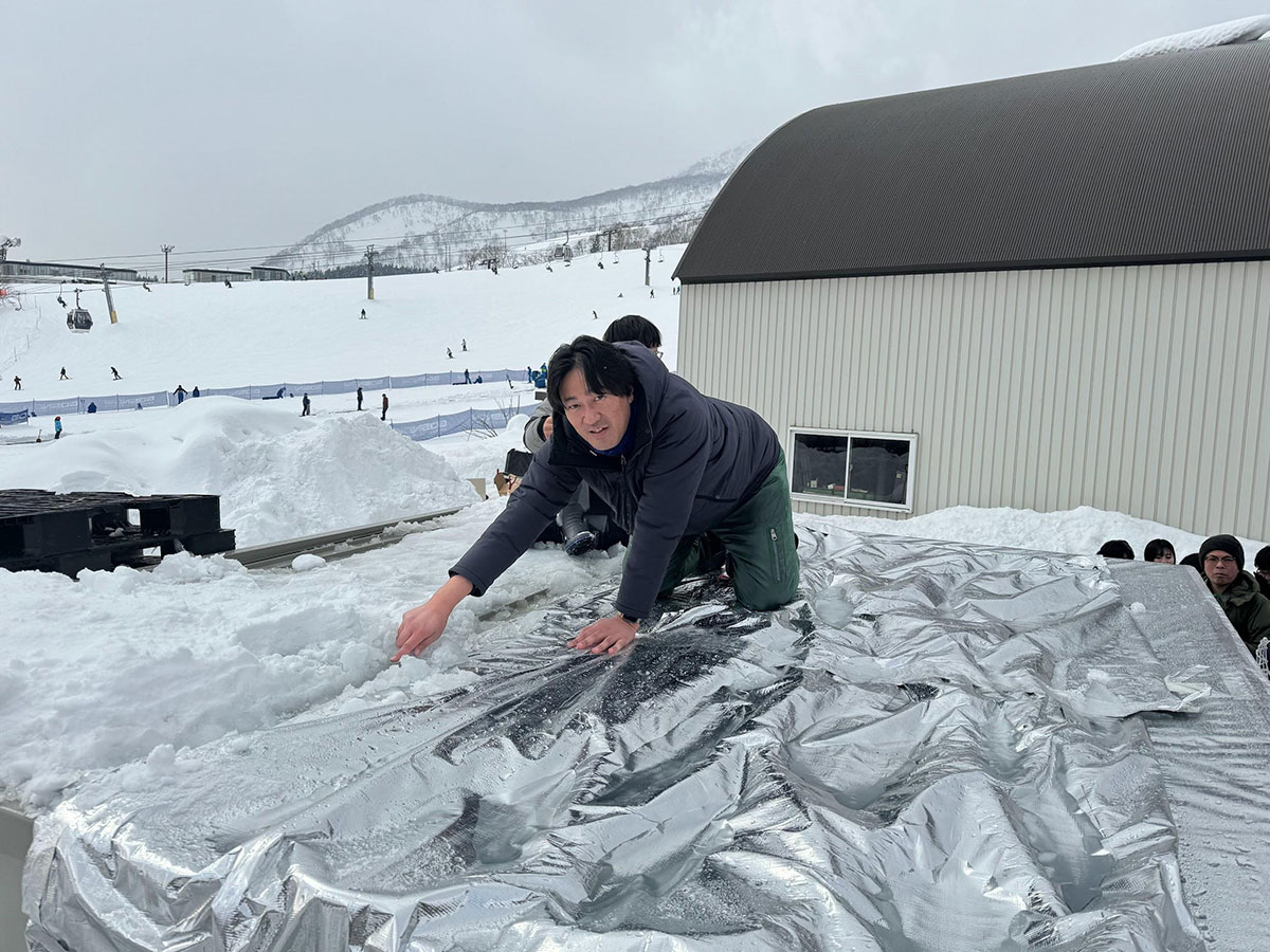 写真）建物の屋根で融雪実証実験のデモンストレーションをする榎木准教授。2024年1月18日　ニセコ東急 グラン・ ヒラフスキー場の駐車場にて